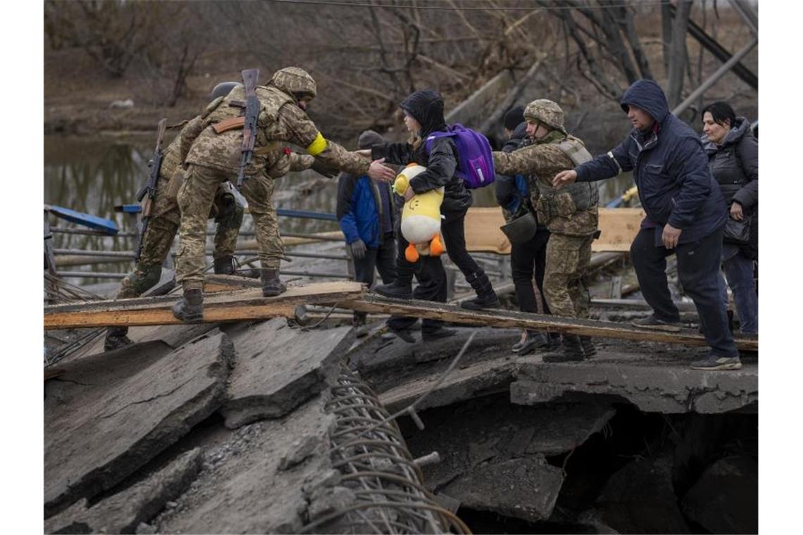 Russland setzt Angriff auf Mariupol fort Ukrainische Soldaten helfen einer fliehenden Familie bei der Überquerung des Flusses Irpin in den Außenbezirken von Kiew. Foto: Emilio Morenatti/AP/dpa