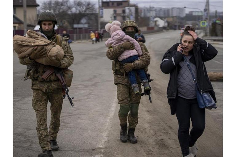 Ukrainische Soldaten in einem Außenbezirk von Kiew helfen einer fliehenden Familie bei der Suche nach einem Fahrzeug. Die US-Regierung geht davon aus, dass russische Soldaten in der Ukraine Kriegsverbrechen begehen. Foto: Emilio Morenatti/AP/dpa