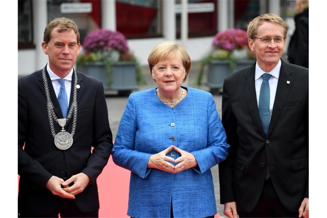Merkel fordert Bekenntnis zur Eigenverantwortung Ulf Kämpfer, Kieler Oberbürgermeister, Bundeskanzlerin Merkel und Daniel Günther, Ministerpräsident von Schleswig-Holstein, stehen im Rahmen der zentralen Feier zum Tag der Deutschen Einheit zusammen. Foto: Carsten Rehder/dpa