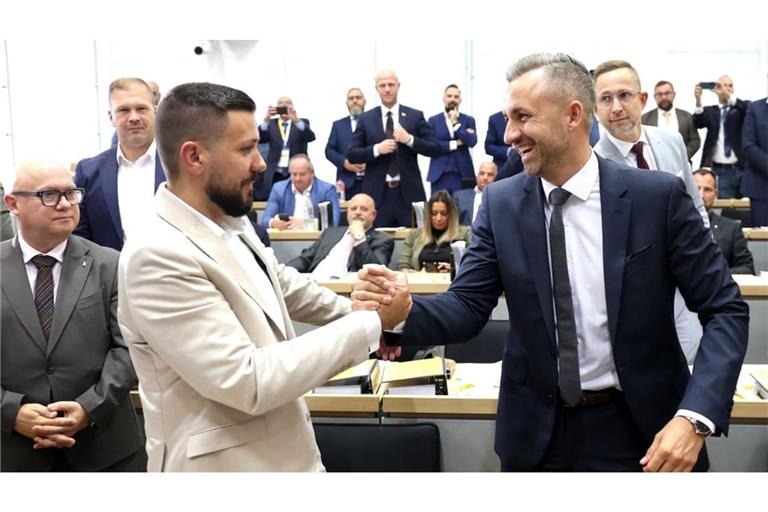 Ulrich Siegmund gratuliert dem neu gewählten Landtagspräsidenten Tobias Rausch im weißen Anzug.