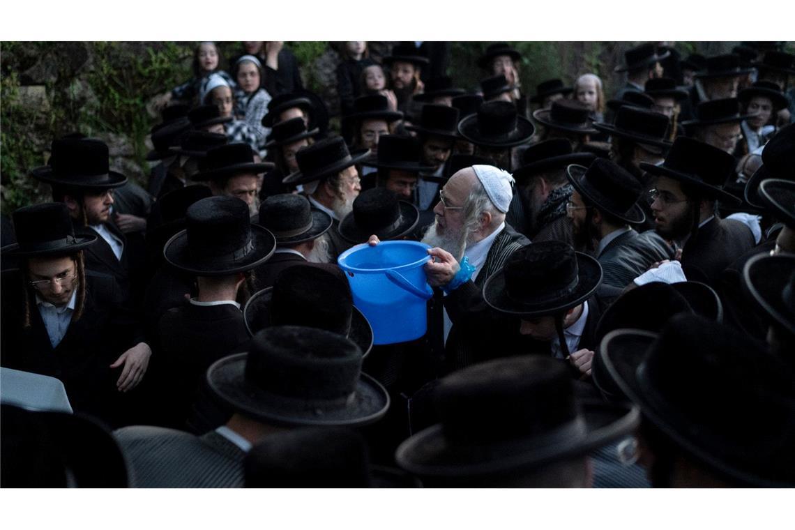 Ultraorthodoxe jüdische Männer sammeln Wasser aus einer Quelle, um ein traditionelles ungesäuertes Brot für das Pessach-Fest an einer Bergquelle in den Außenbezirken von Jerusalem zu backen.