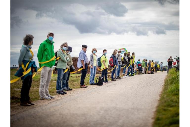 Umwelt- und Klimaschützer sowie Bewohner der angrenzenden Dörfer bilden am Rande des Braunkohletagebaus Garzweiler eine Menschenkette. Foto: Malte Krudewig/dpa