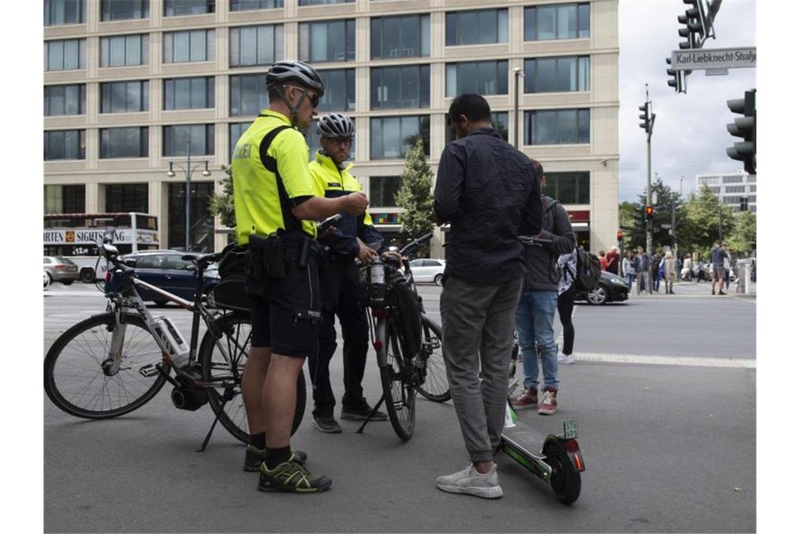 Und noch eine neue Aufgabe: Polizisten der Berliner Fahrradstaffel kontrollieren auf einem Bürgersteig zwei Jugendliche mit E-Tretrollern. Foto: Paul Zinken