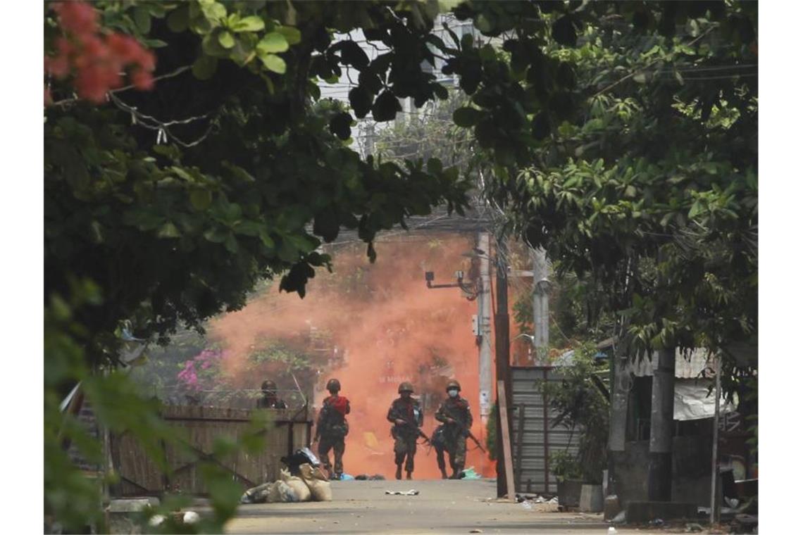 Auswärtiges Amt empfiehlt Ausreise aus Myanmar Uniformierte Soldaten mit Gewehren gehen in Yongon während einer Demonstration von Anti-Putsch-Demonstranten auf eine Rauchwolke zu. Foto: -/AP/dpa