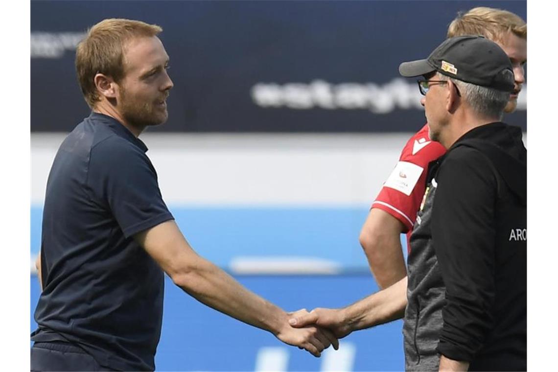 Union-Trainer Urs Fischer (r) gratuliert TSG-Trainer Matthias Kaltenbach zum Sieg seiner Mannschaft. Foto: Thomas Kienzle/AFP Pool/dpa