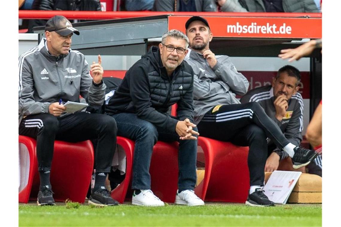 Unions Co-Trainer Markus Hoffmann, Trainer Urs Fischer und Co-Trainer Sebastian Bönig (l-r) sitzen auf Bank. Foto: Andreas Gora/dpa