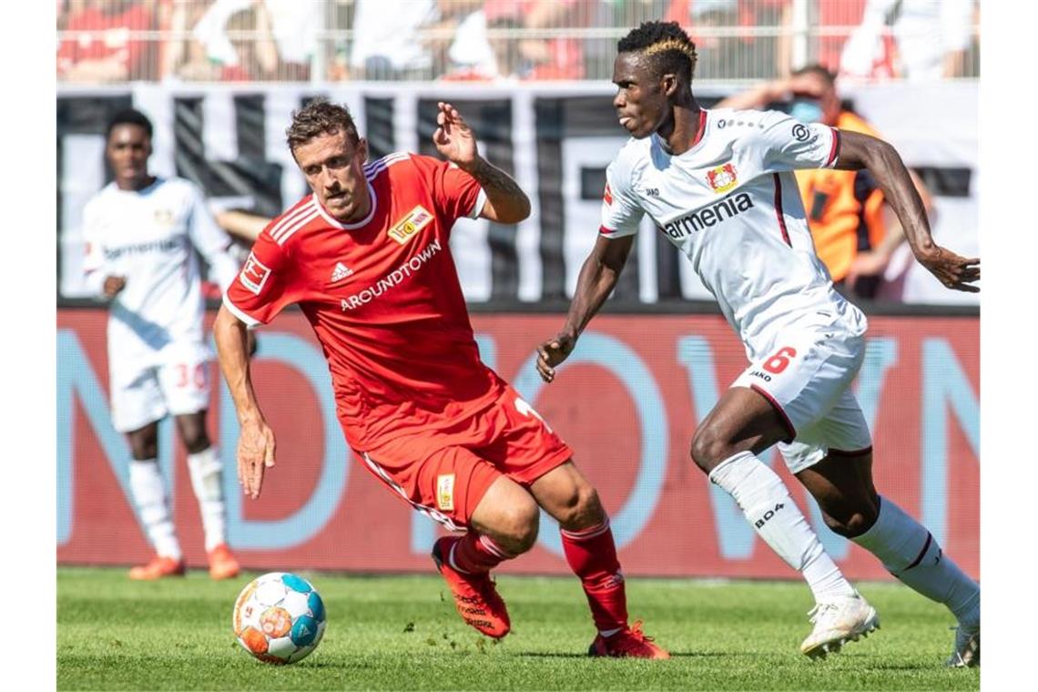 Unions Max Kruse (l) kämpft mit dem Leverkusener Neuzugang Odilon Kossounou um den Ball. Foto: Andreas Gora/dpa