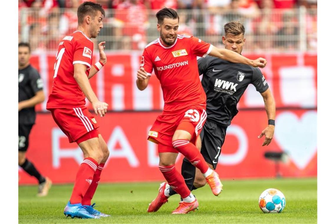 Bayern siegt in Leipzig - Dortmund gewinnt Spektakel Unions Niko Gießelmann (M) im Laufduell mit dem Augsburger Florian Niederlechner (r). Foto: Andreas Gora/dpa
