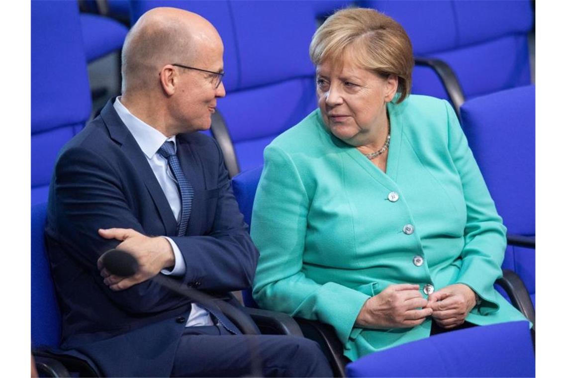 Unionsfraktionschef Ralph Brinkhaus und Kanzlerin Angela Merkel sprechen im Bundestag miteinander. Foto: Tom Weller