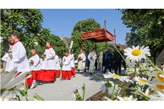Unter einem Stoffbaldachin wird die Monstranz während der Fronleichnamsprozession am 8. Juni 2023 durch die Straßen des Dorfes Obermarchtal  getragen.