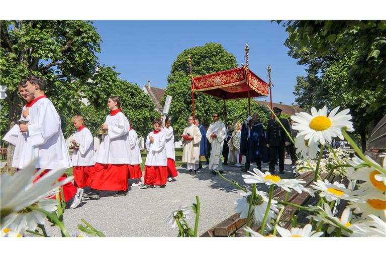 Unter einem Stoffbaldachin wird die Monstranz während der Fronleichnamsprozession am 8. Juni 2023 durch die Straßen des Dorfes Obermarchtal  getragen.
