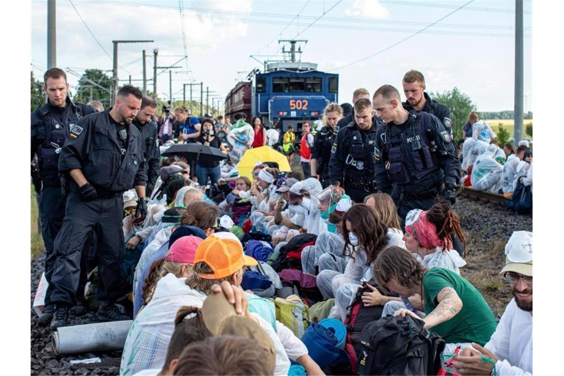 Unter Polizeibeobachtung aus nächster Nähe: Aktivisten blockieren am Freitag die Gleise der Kohle-Transportbahn. Foto: Christoph Reichwein