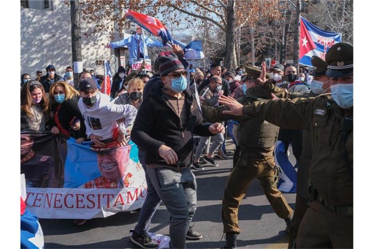 Unterstützer der kubanischen Regierung stoßen vor der kubanischen Botschaft auf Gegendemonstranten, die Plakate mit Bildern vom chilenischen Diktator Pinochet tragen. Foto: Daniel Araya Martin/Agencia Uno/dpa