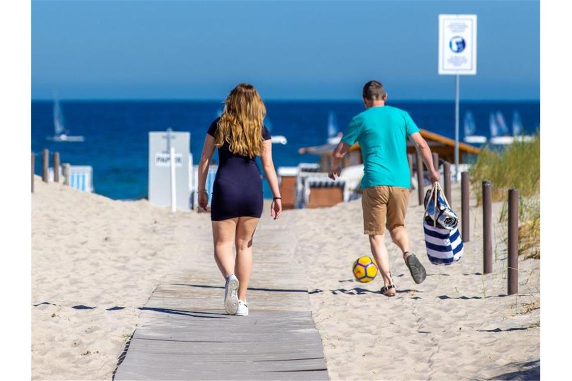 Hoch „Steffen“ bringt den Sommer Urlauber gehen über einen Zugang zum Ostseestrand. Foto: Jens Büttner/dpa-Zentralbild/dpa