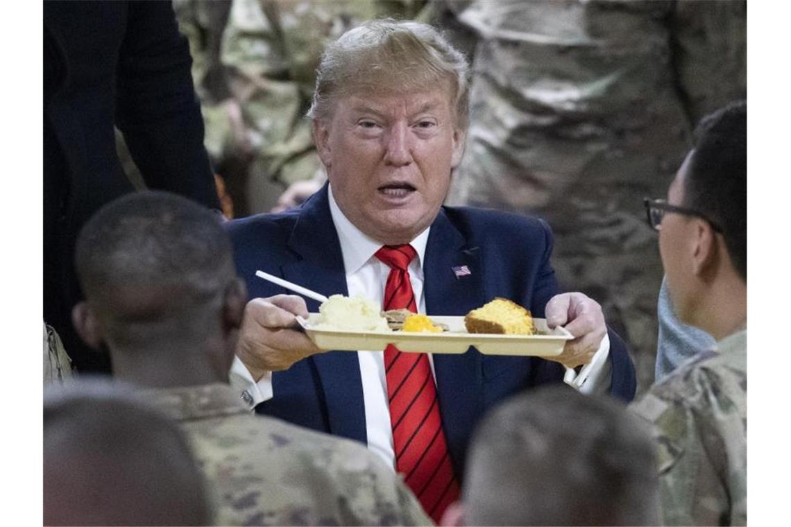 US-Präsident Donald Trump hält bei einem Besuch von amerikanischen Truppen ein Tablett mit Essen in der Hand. Foto: Alex Brandon/AP/dpa