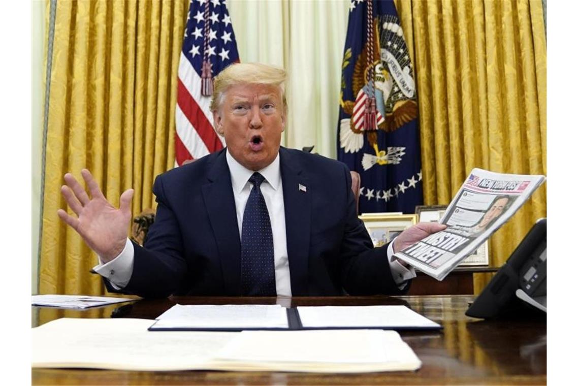 US-Präsident Donald Trump zeigt im Oval Office das Titelblatt der Zeitung „New York Post“ mit dem Titel „Ministry of Tweet“ („Ministerium des Tweets“). Foto: Evan Vucci/AP/dpa