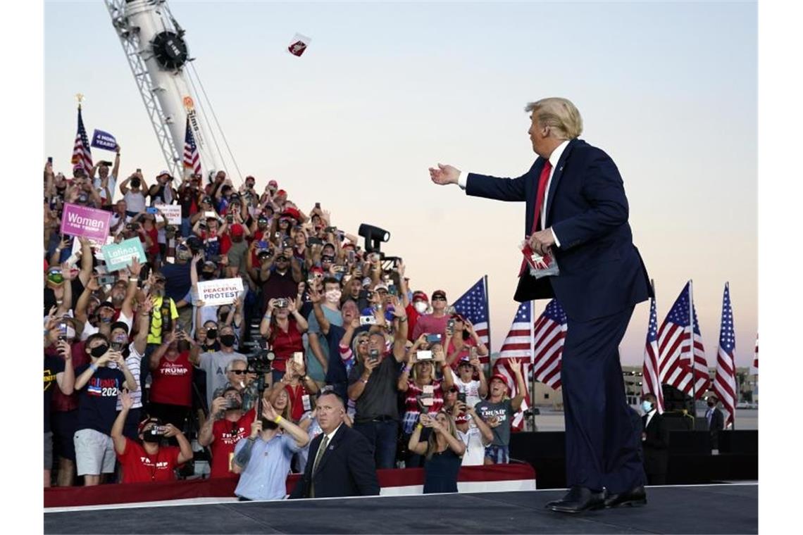 US-Präsident Trump wirft Gesichtsmasken in die Menge, als er zu einer Wahlkampfkundgebung am Orlando Sanford International Airport eintrifft. Foto: Evan Vucci/AP/dpa