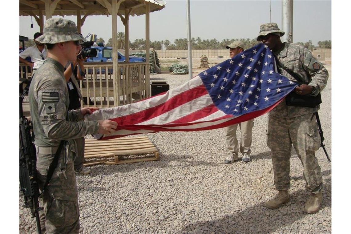US-Soldaten falten in einem Militärstützpunkt im Irak ihre Flagge zusammen. Vielleicht bald für immer?. Foto: Khider Abbas/epa/dpa