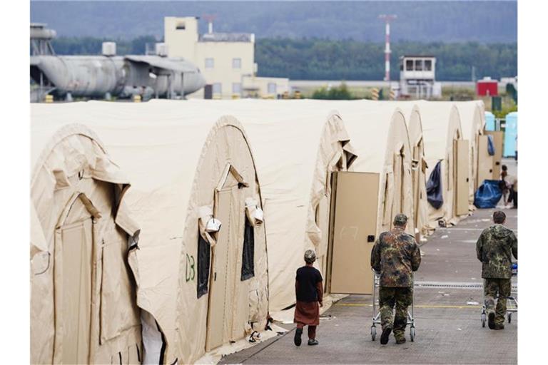 US-Soldaten gehen auf der Ramstein Air Base mit Einkaufswagen an einer Reihe von Zelten vorbei. Foto: Uwe Anspach/dpa