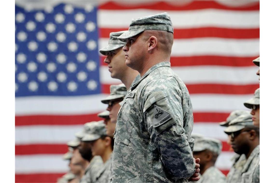 US-Soldaten stehen vor der amerikanischen Flagge. Foto: Frank May/dpa/archiv