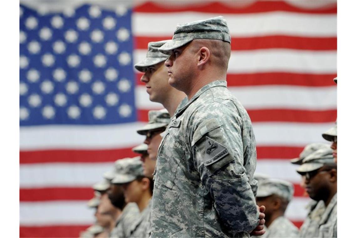 US-Soldaten stehen vor einer US-Flagge. Foto: Frank May/dpa