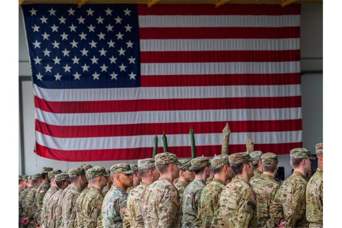 US-Soldaten während einer militärischen Zeremonie in den Storck-Barracks vor einer Flagge der Vereinigten Staaten von Amerika. Foto: Nicolas Armer/dpa