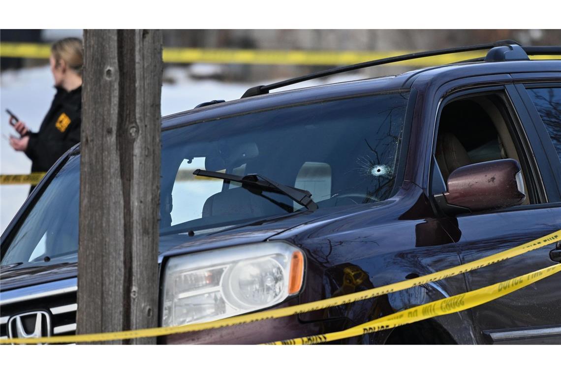 USA, Minneapolis: Ein Einschussloch ist in der Windschutzscheibe zu sehen, während Polizeibeamte am Tatort einer Schießerei arbeiten.