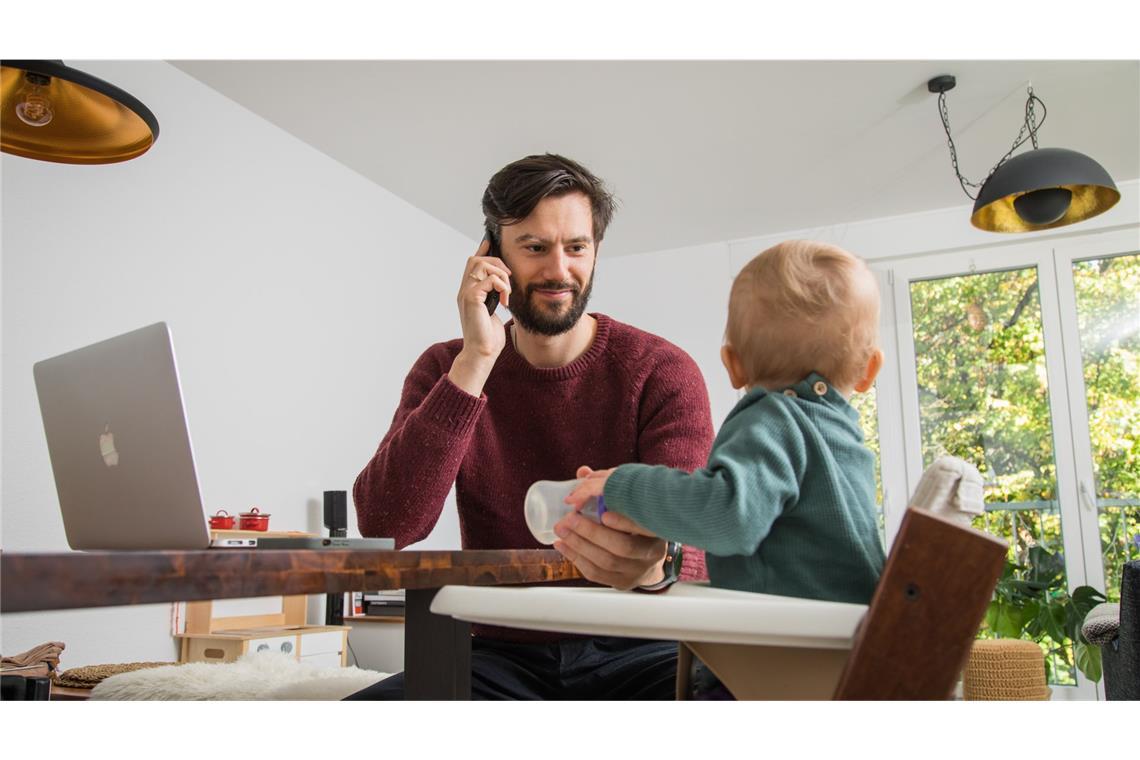 Homeoffice-Kürzung bei VW sorgt für Unruhe Vater mit Baby im Homeoffice.