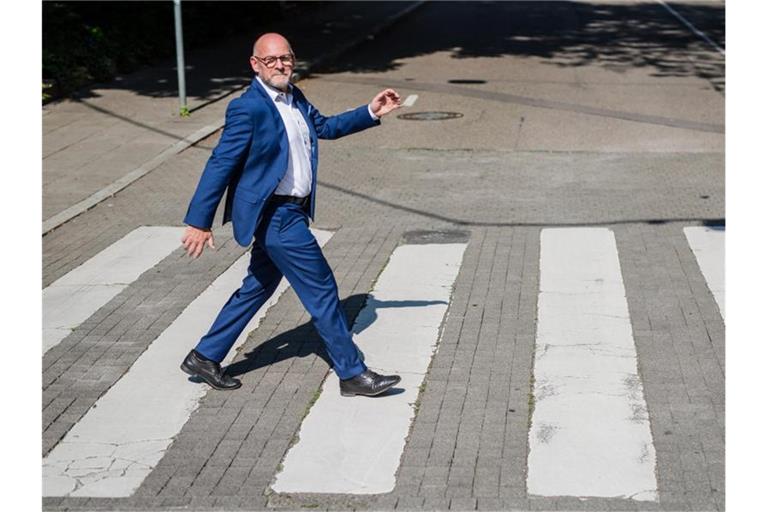 Verkehrsminister Winfried Hermann (Grüne) läuft bei einem Fotoshooting über einen Zebrastreifen. Foto: Christoph Schmidt/dpa/Archivbild