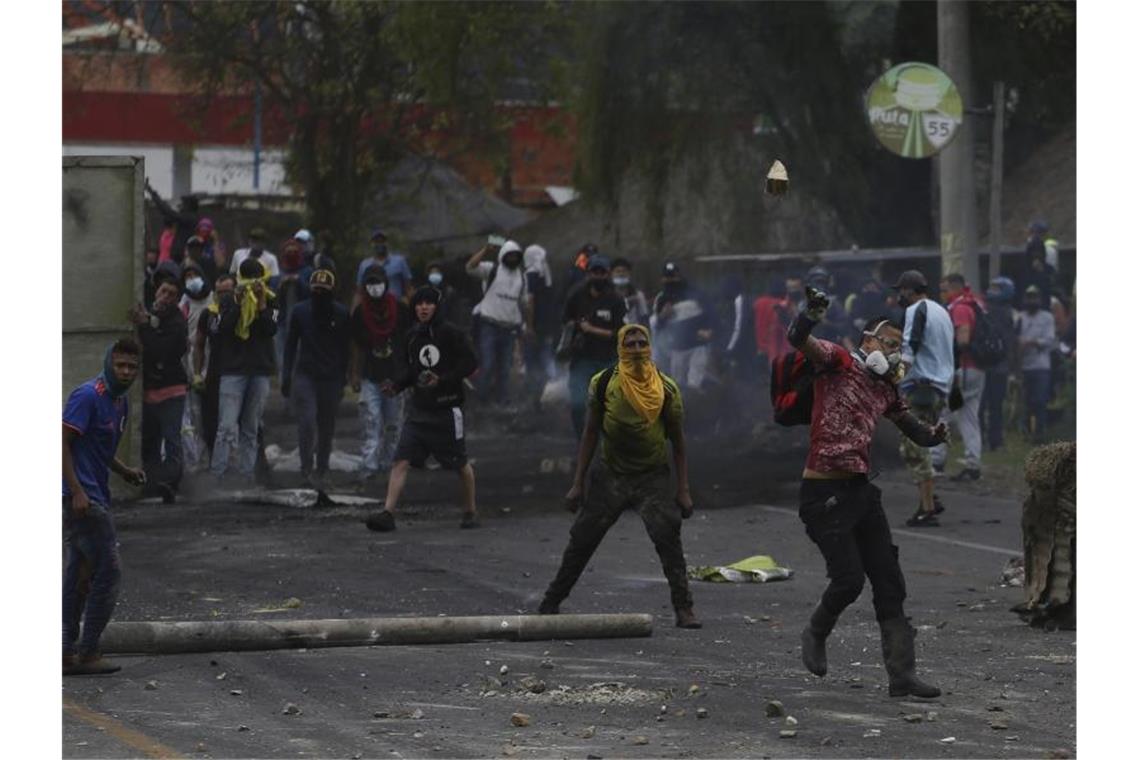 Vermummte Anti-Regierungs-Demonstranten werfen in Gachancipa Steine auf die Sicherheitskräfte während anhaltender Proteste. Foto: Ivan Valencia/AP/dpa