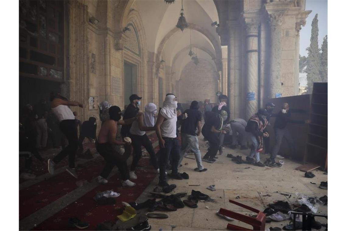 Vermummte Palästinenser werfen mit Steinen auf israelische Sicherheitskräfte. Foto: Mahmoud Illean/AP/dpa