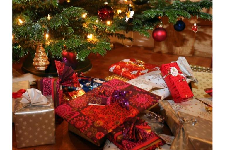 Verpackte Weihnachtsgeschenke liegen unter einem Christbaum. Foto: Karl-Josef Hildenbrand/dpa