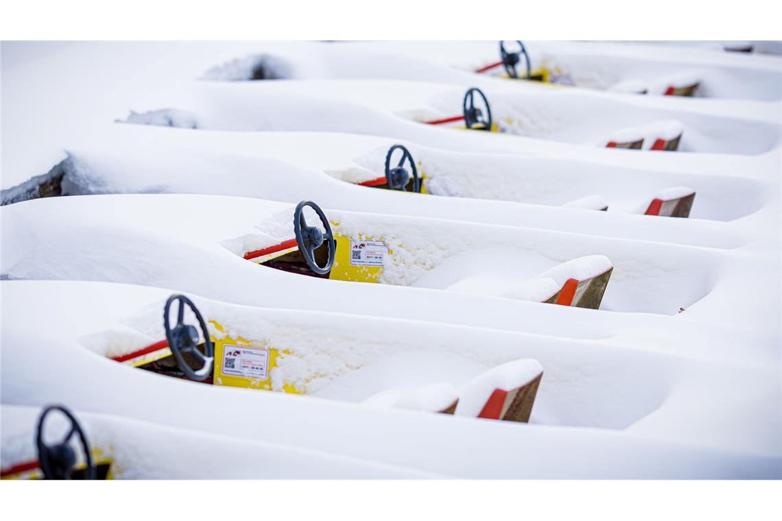 Verschneite Tretboote liegen im zugefrorenen Maschsee