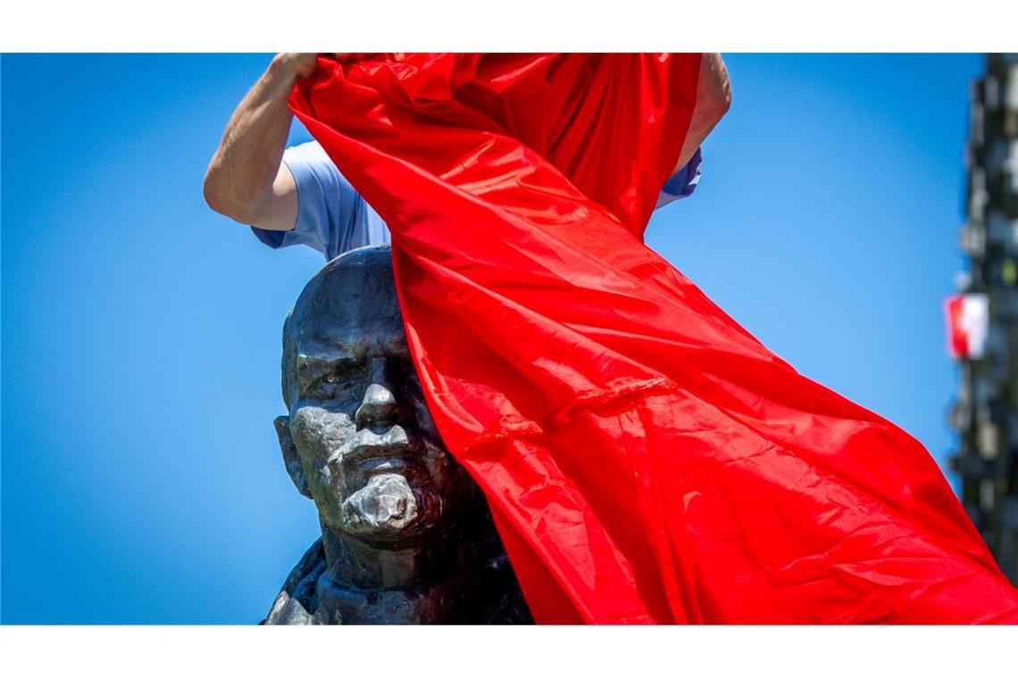 Bilder des Tages Vertreter von Opferverbänden verhüllen bei einer Kundgebung in Schwerin eines der letzten Lenin-Denkmäler in Deutschland und protestieren damit gegen die öffentlichen Ehrungen der Repräsentanten von Systemen der Gewaltherrschaft.