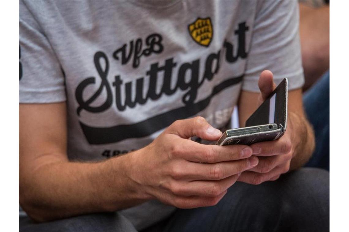 VfB-Mitglied hält während der Versammlung sein Smartphone in seinem Händen. Foto: Christoph Schmidt