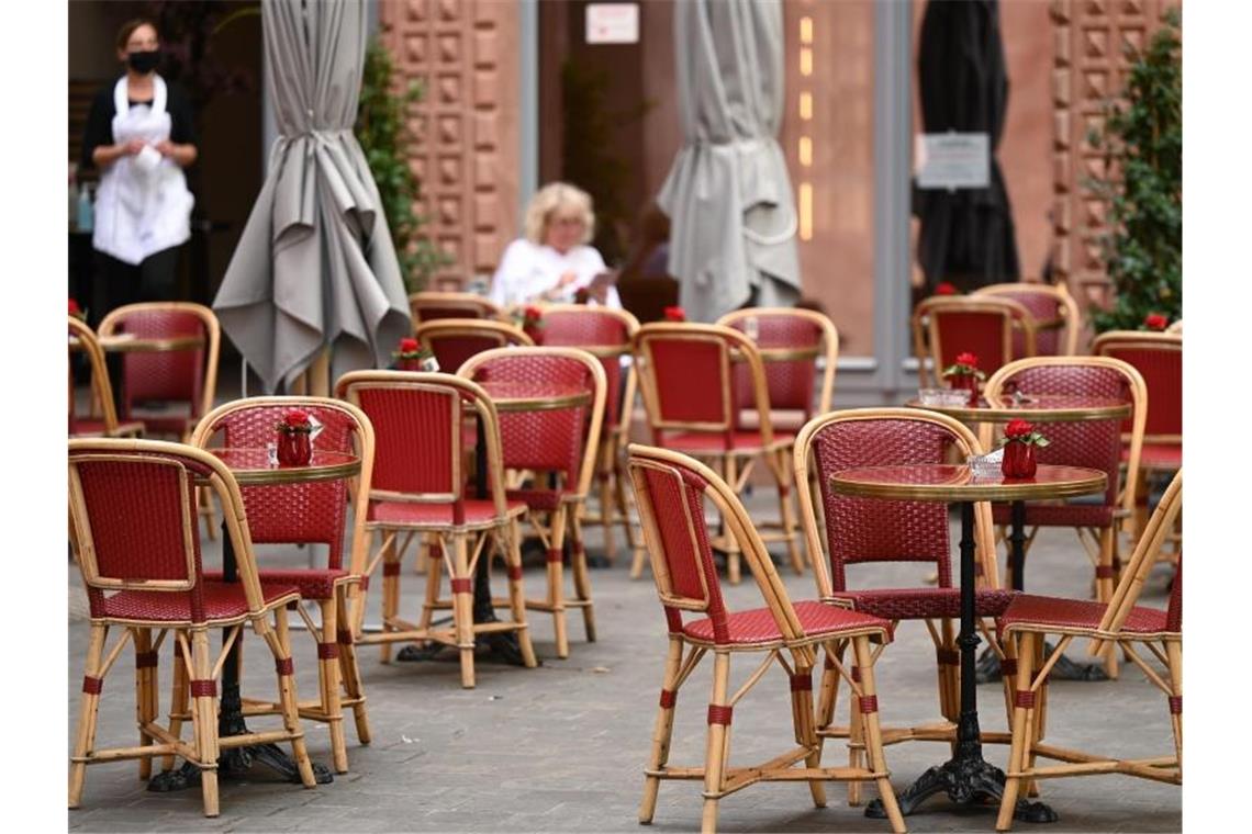 Viele freie Tische vor einem Café in Frankfurt. Foto: Arne Dedert/dpa