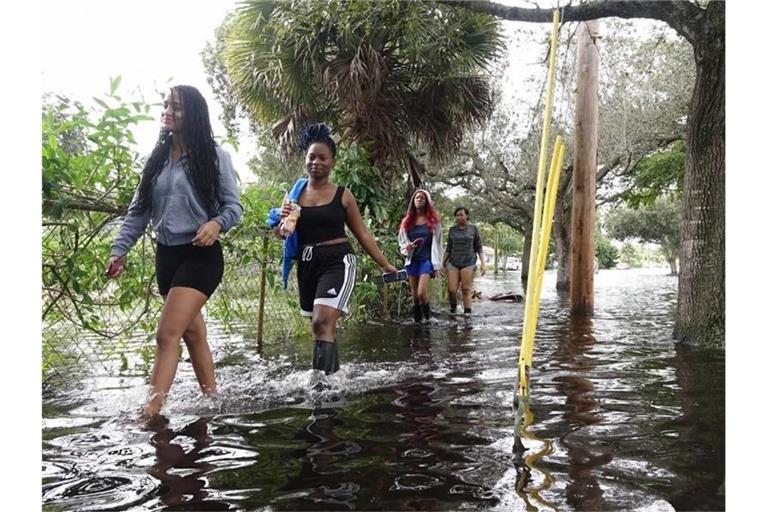 Vier junge Frauen waten durch das Hochwasser nach starken Regenfällen ausgelöst von Tropensturm „Eta“ nördlich des Broward Boulevards in Florida. Foto: Joe Cavaretta/TNS via ZUMA Wire/dpa
