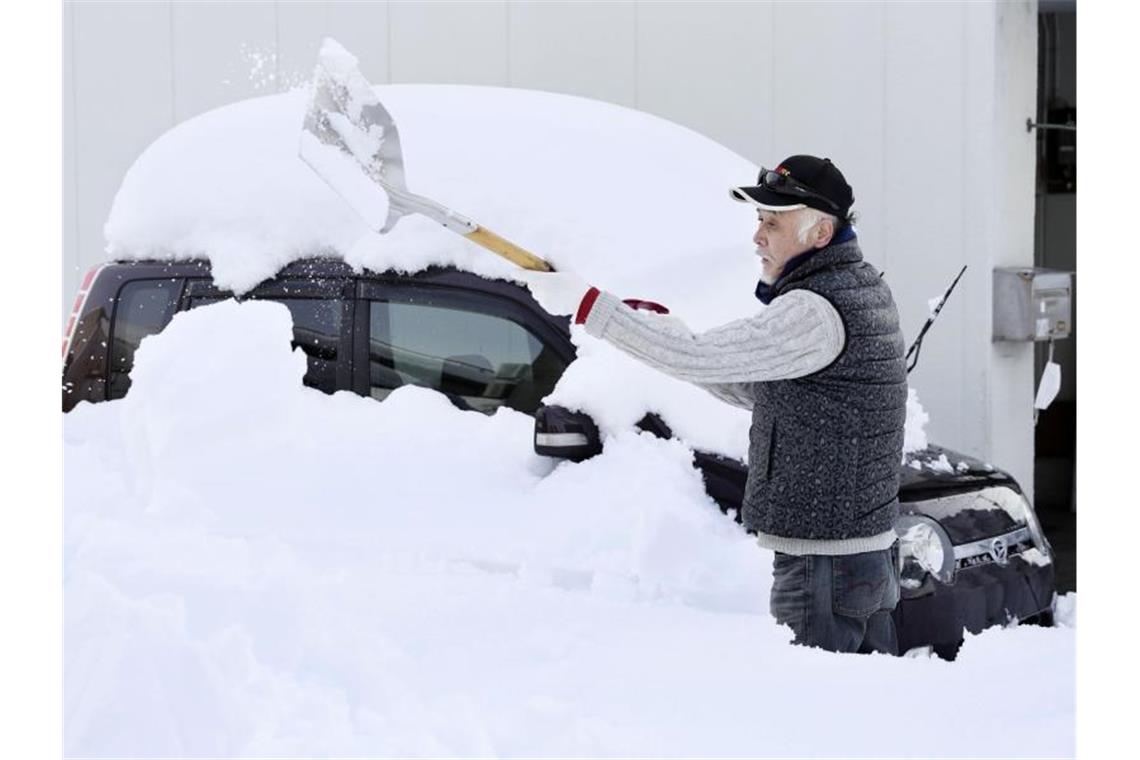 Schneefälle haben Japan weiter im Griff Völlig bedeckt von Neuschnee: Ein Mann in Fukui schaufelt sein Auto frei. Foto: --/kyodo/dpa