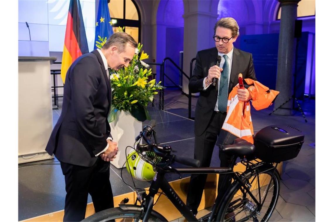 Volker Wissing (FDP, l), Bundesminister für Verkehr und Digitales, nimmt von Andreas Scheuer (CSU), scheidender Bundesminister für Verkehr und digitale Infrastruktur, bei der Amtsübergabe im Bundesministerium für Verkehr und Digitales einen Fahrradhelm und weitere Ausrüstung entgegen. Foto: Christoph Soeder/dpa