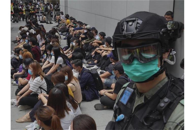 Von Bereitschaftspolizisten festgehaltene regierungskritische Demonstranten sitzen auf dem Boden im Central District von Hongkong. Foto: Vincent Yu/AP/dpa