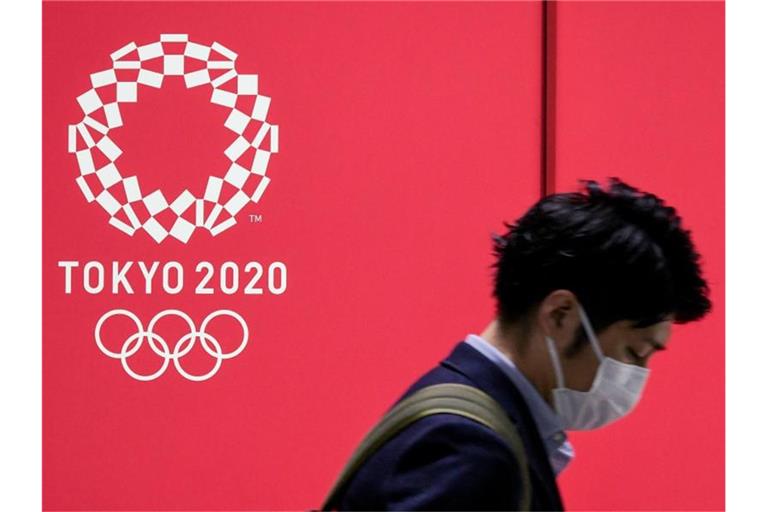 Von Euphorie ist in Japan vor den Sommerspielen wenig zu spüren: Ein Mann mit Mund-Nasen-Schutz geht an einem Werbeplakat vorbei. Foto: Cezary Kowalski/SOPA Images via ZUMA Wire/dpa