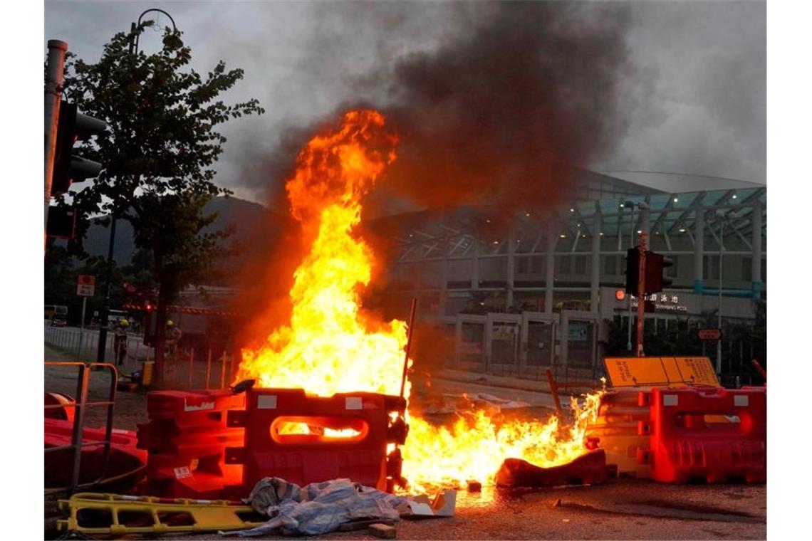 Proteste in Hongkong - Ist China „bereit für den Kampf“? Von prodemokratischen Demonstranten vor dem Flughafen errichtete Barrikaden stehen in Flammen. Foto: Vincent Yu/AP