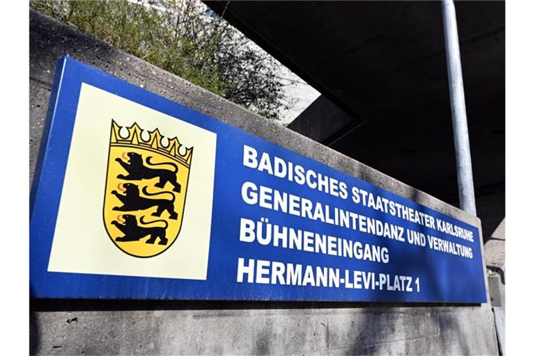 Vor dem Badischen Staatstheater hängt ein Schild. Foto: Uli Deck/dpa