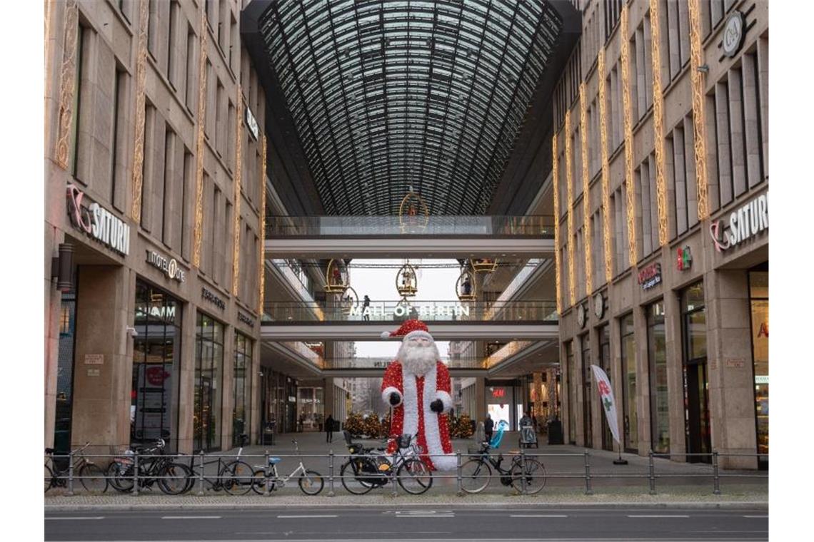 Vor dem Einkaufszentrum „Mall of Berlin“ steht eine Weihnachtsmann-Skulptur. Der Bund will in der Corona-Krise schärfere Auflagen für den Einzelhandel. Foto: Christophe Gateau/dpa