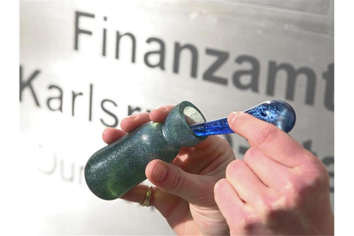 Vor dem Finanzamt Karlsruhe Stadt wird ein Flacon mit dem Parfüm Aerarium gezeigt. Foto: Uli Deck/dpa/Archivbild