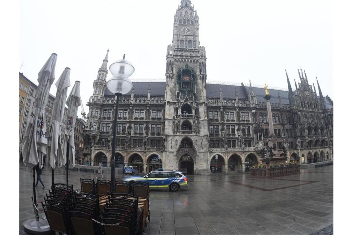 Vor dem Müncher Rathaus fährt ein Polizeiauto über den leeren Marienplatz. Foto: Felix Hörhager/dpa