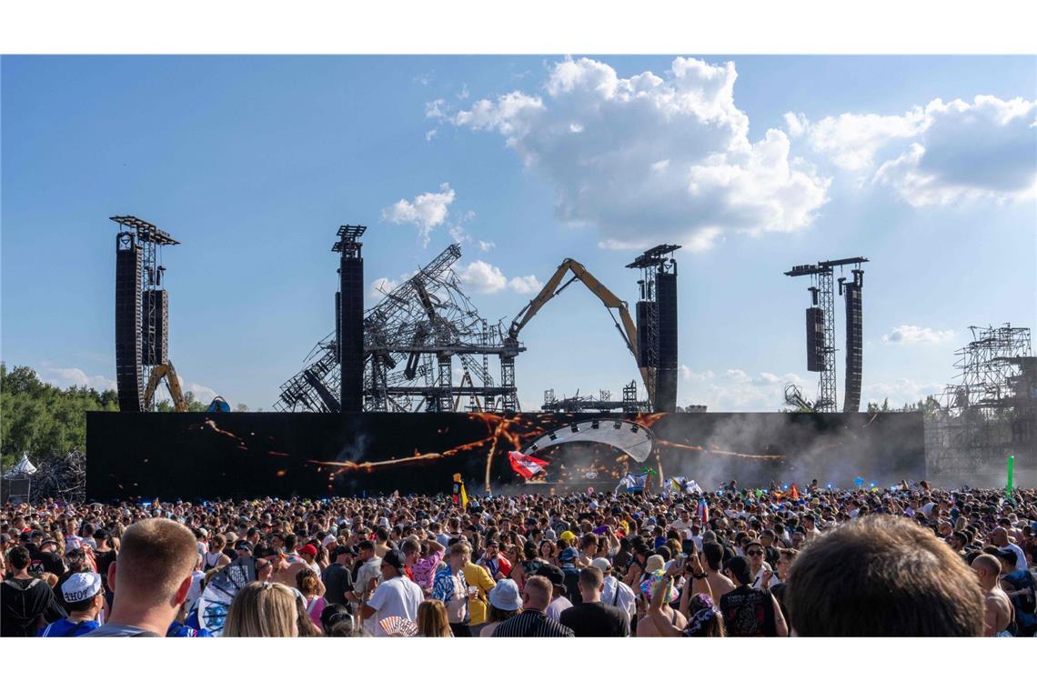 Vor der Kulisse der niedergebrannten Hauptbühne in Boom feiern die Festivalbesucher.