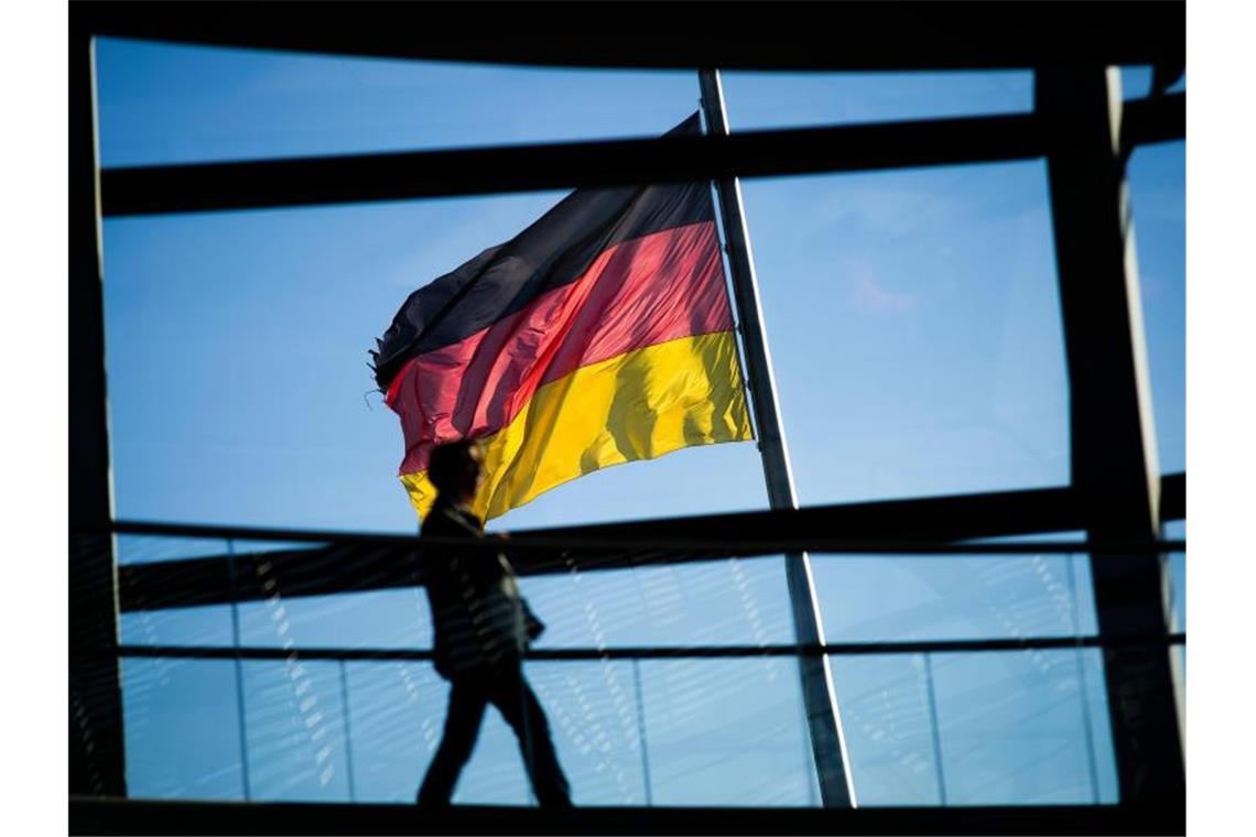 Deutsche zählen in Sachen Wohlbefinden zur Spitzengruppe Vor der Kuppel des Reichstaggebäudes weht die Deutschlandfahne. In einem internationalen Ranking zum Wohlbefinden der Bevölkerung schneidet Deutschland gut ab. Foto: Gregor Fischer/dpa