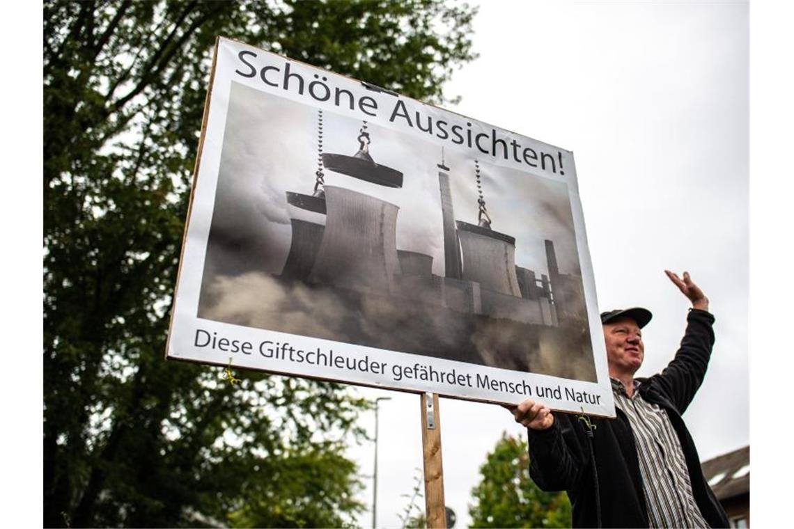Vor der Verhandlung beim Oberverwaltungsgericht um das Kohlekraftwerk Datteln 4 steht ein Klimaaktivist und protestiert mit einem Plakat. Foto: Guido Kirchner/dpa