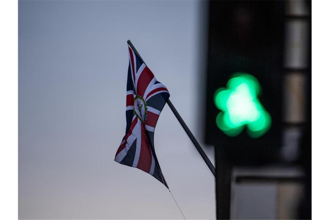 Vor einer wehenden Britischen Flagge leuchtet eine Grüne Ampel. Foto: Christophe Gateau/dpa